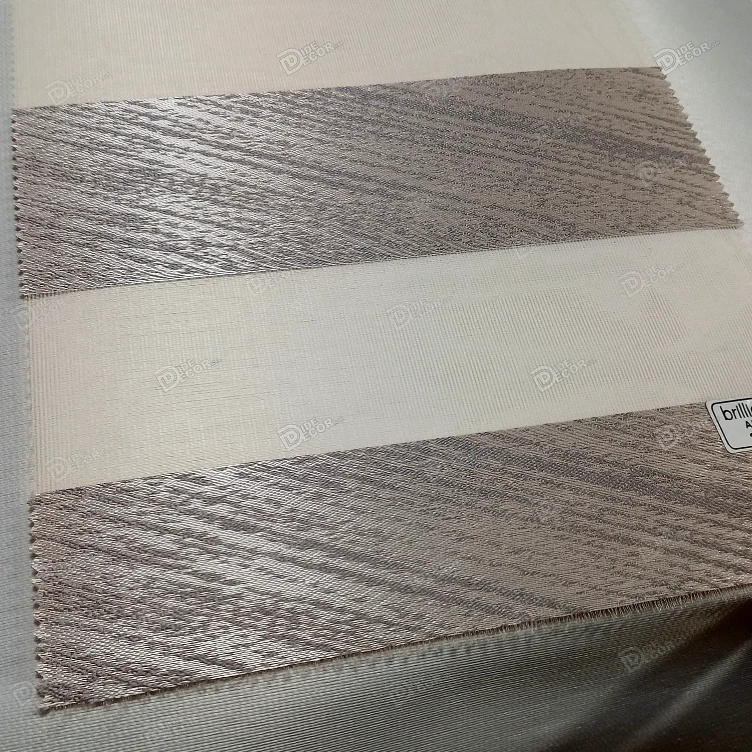 نمونه پارچه پرده زبرا کد T2325 با رنگ طوسی براق و خطوط مورب طوسی تیره که با تغییر زاویه دید، رنگ پارچه تغییر می‌کند.